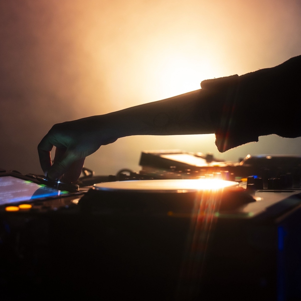 Рука диджея настраивает музыкальный пульт 