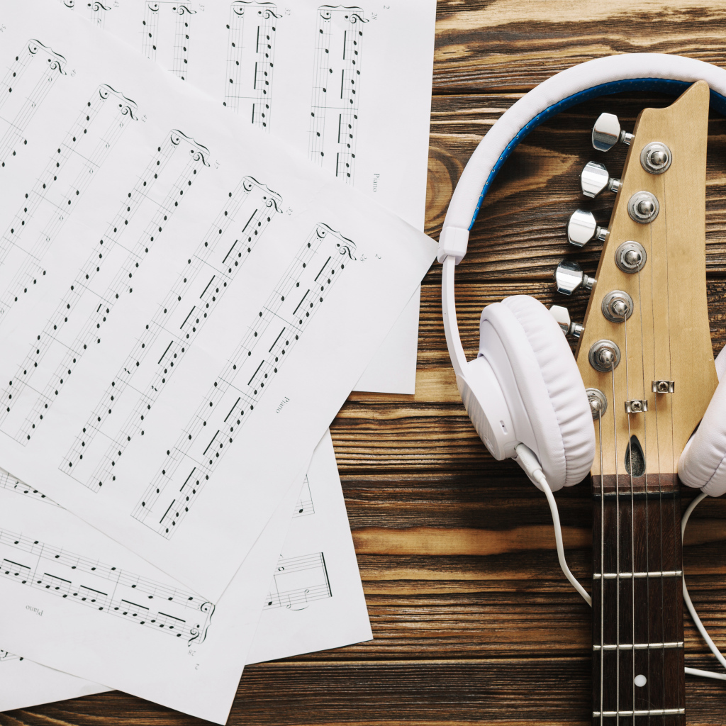 Ноты, наушники и гитара на столе