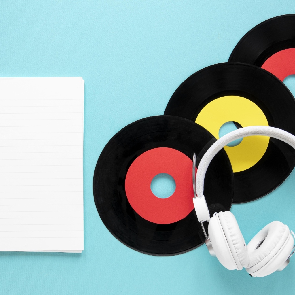 Пластинки на голубом фоне с блокнотом и наушниками