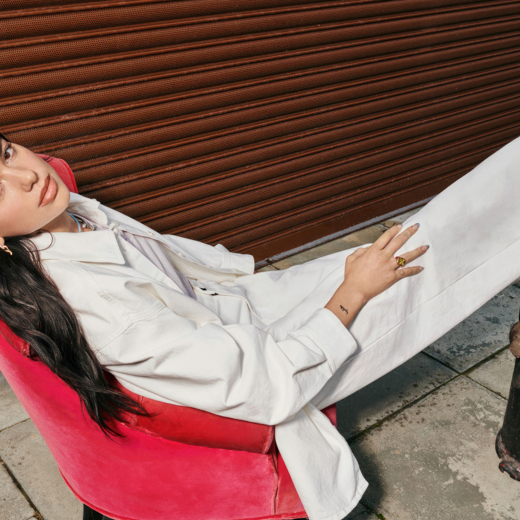 Певица Дуа Липа в белом костюме сидит в кресле