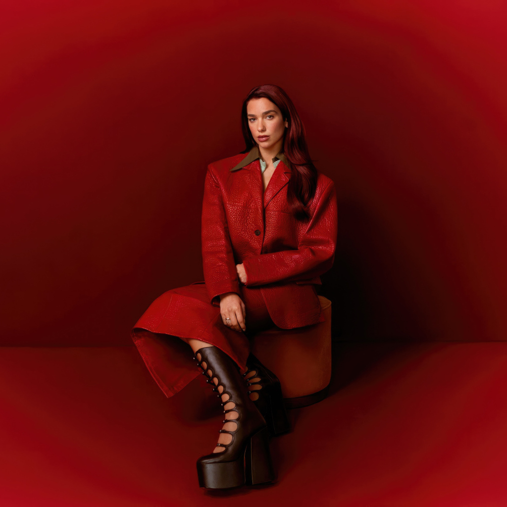 Певица Дуа Липа позирует на красном фоне