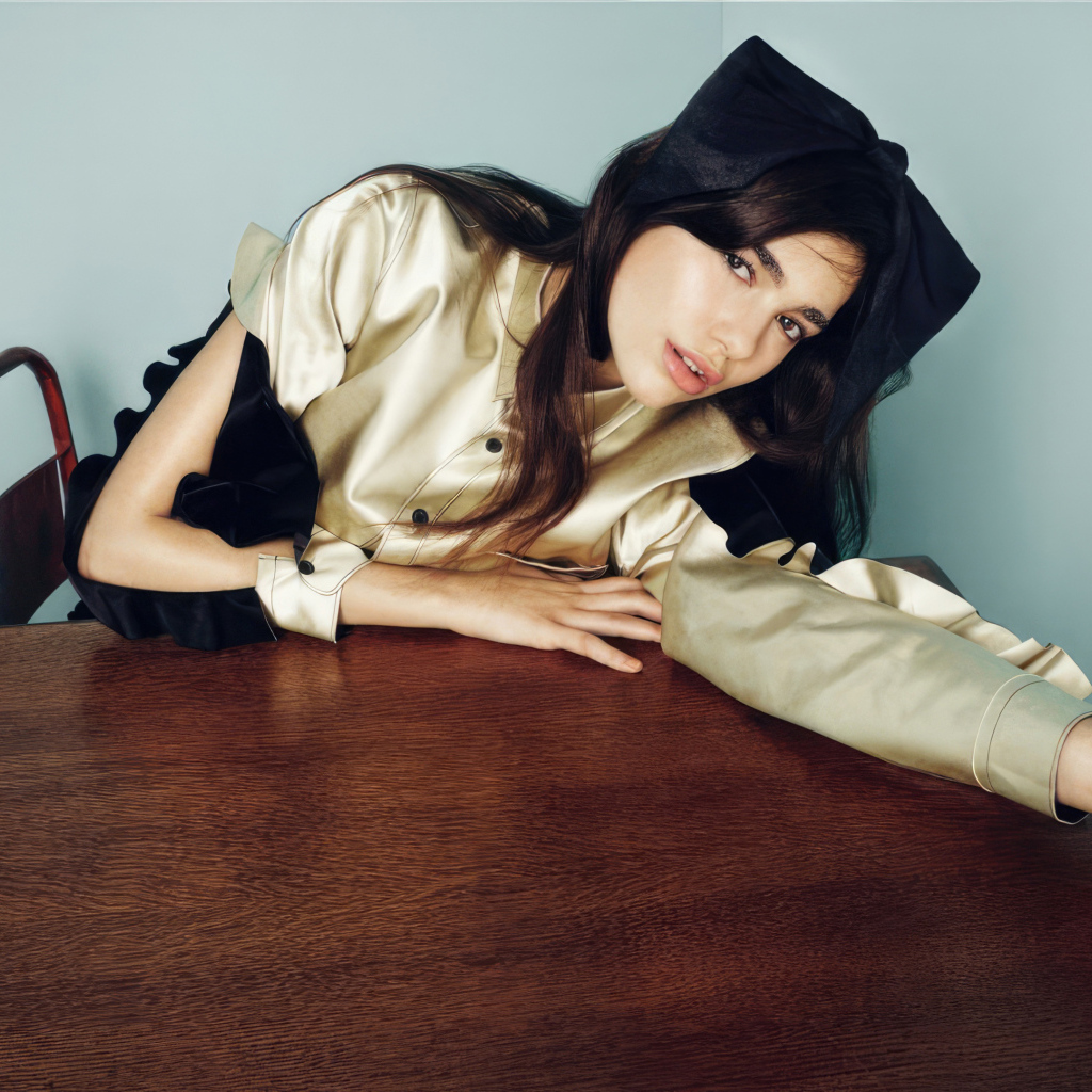 Певица Дуа Липа сидит за деревянным столом