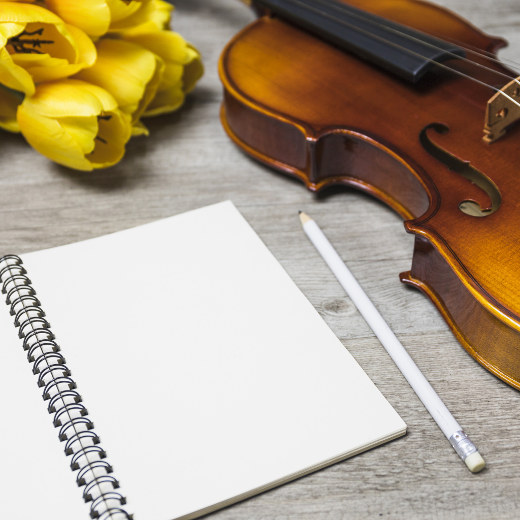 Скрипка, блокнот и желтые тюльпаны на столе