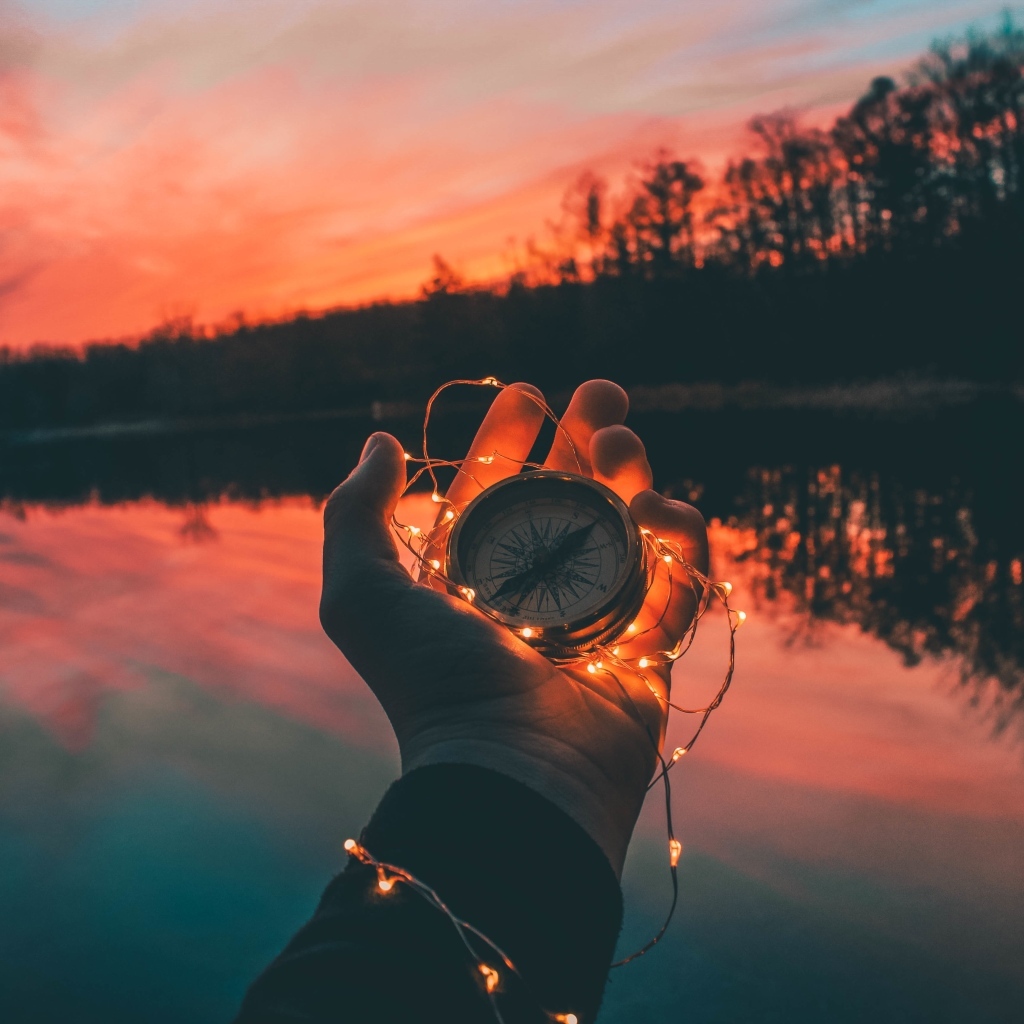 Компас с гирляндой в руке у реки