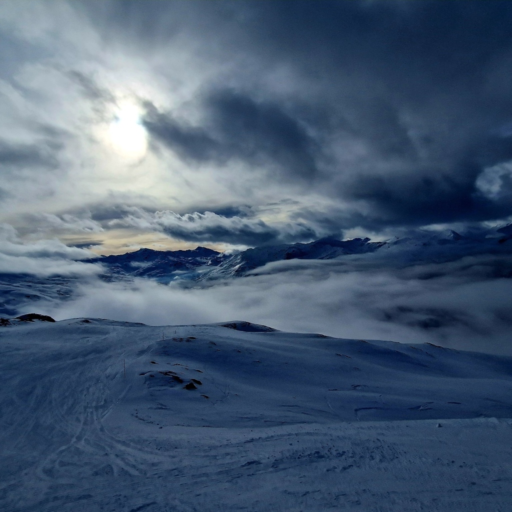 Луна в облачном небе над заснеженными горами