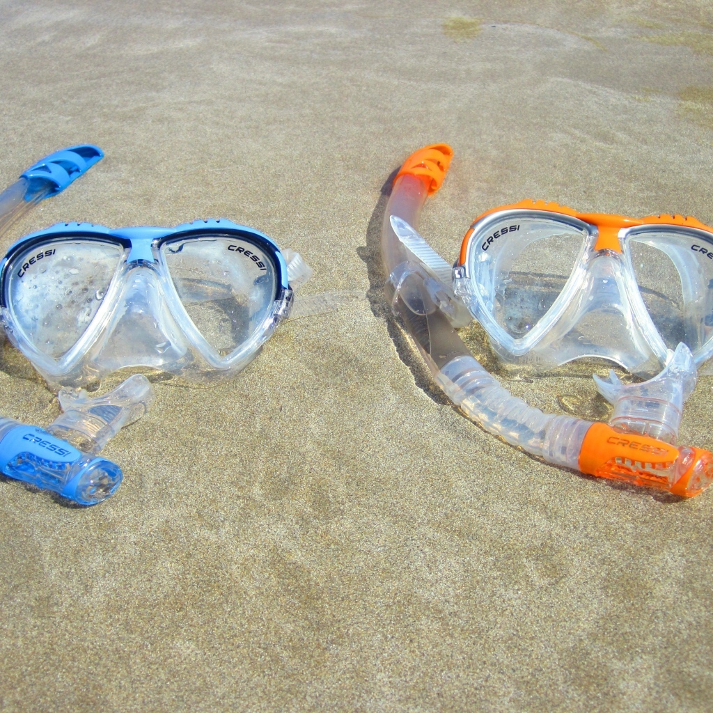 Две маски лежат на мокром морском песке