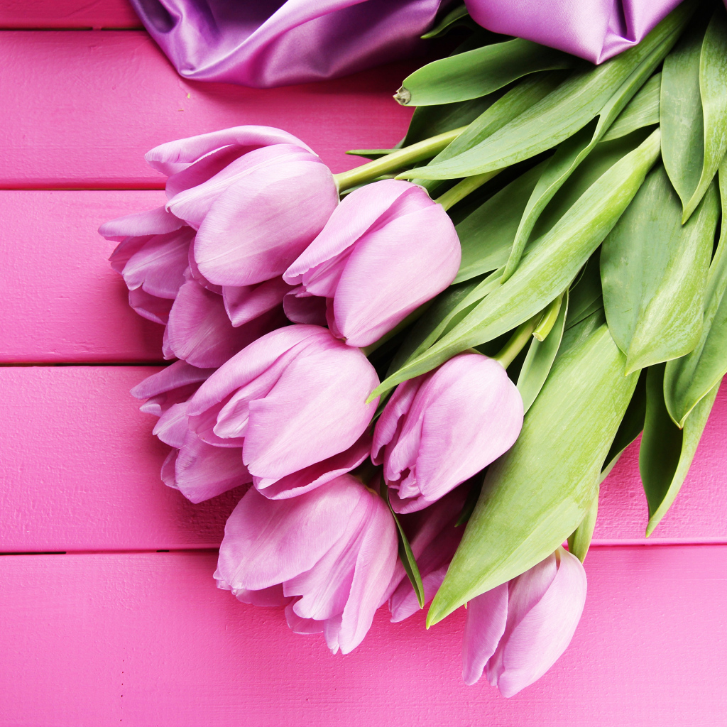 Красивый букет тюльпанов с лентой на розовом столе
