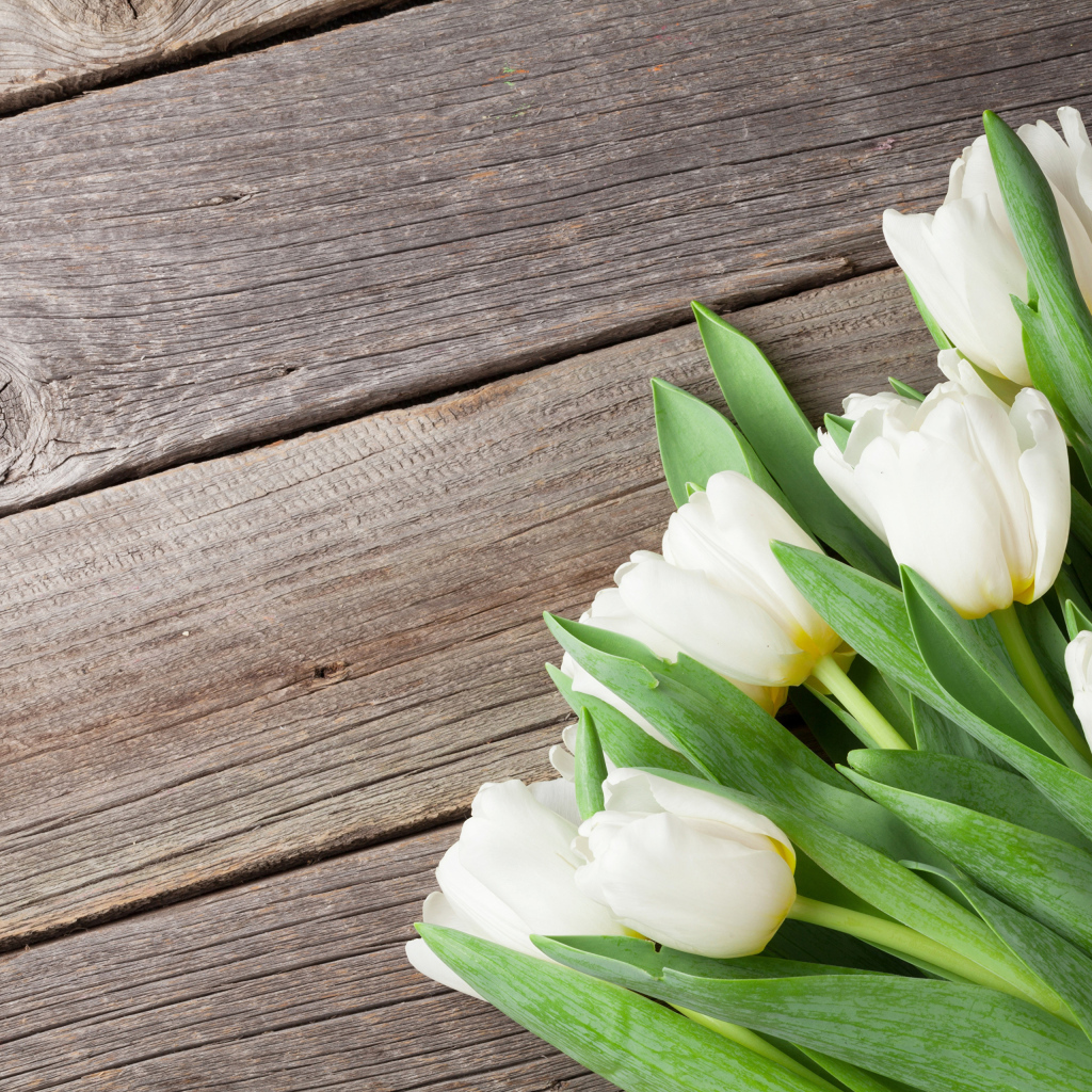 Букет нежных белых тюльпанов с зелеными листьями на деревянном столе