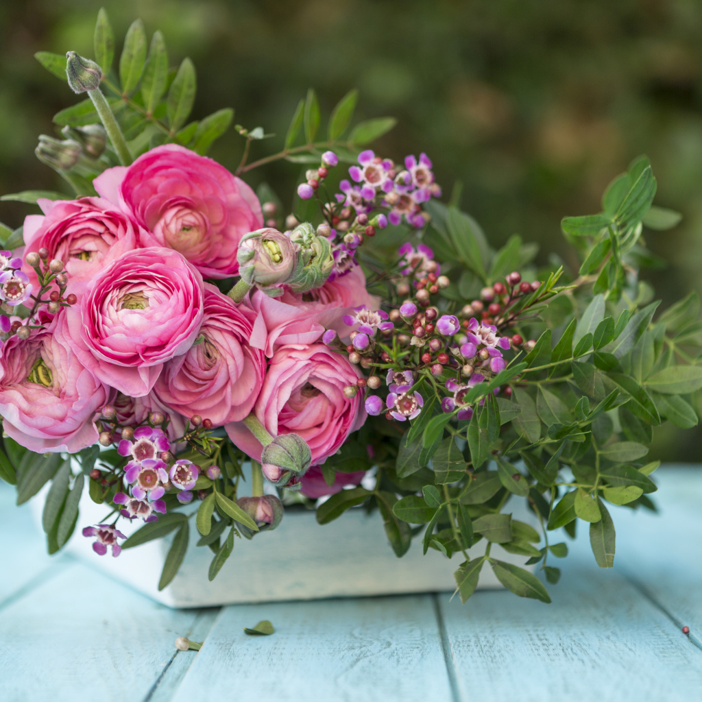 Букет розовых цветов лютика в ящике на голубом столе