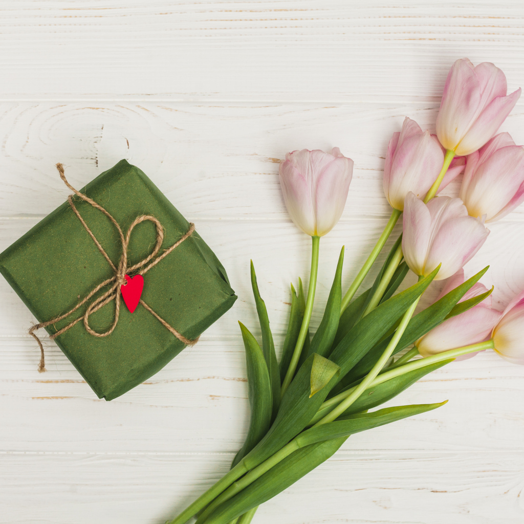 Букет розовых тюльпанов на столе с подарком