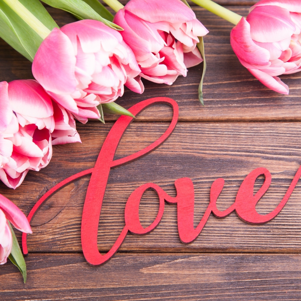 Букет розовых тюльпанов с надписью любовь на деревянном столе