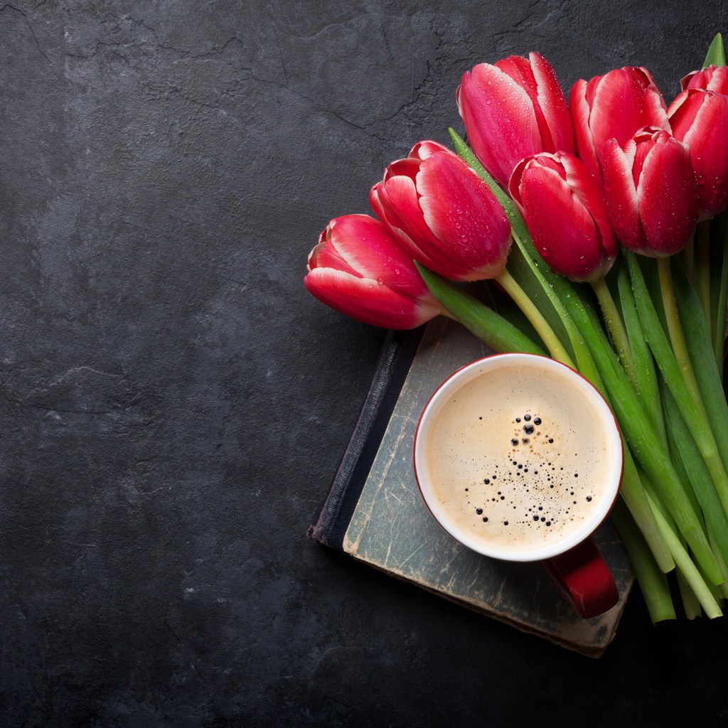 Букет красных тюльпанов с чашкой кофе на черном столе