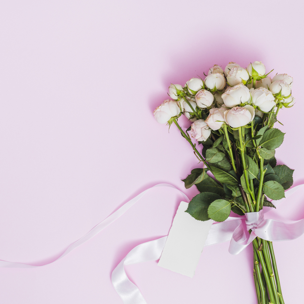 Букет роз с лентой на розовом фоне