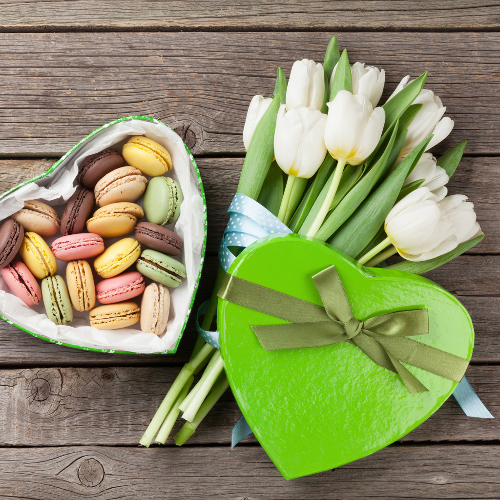 Букет белых тюльпанов на столе с коробкой печенья макарун