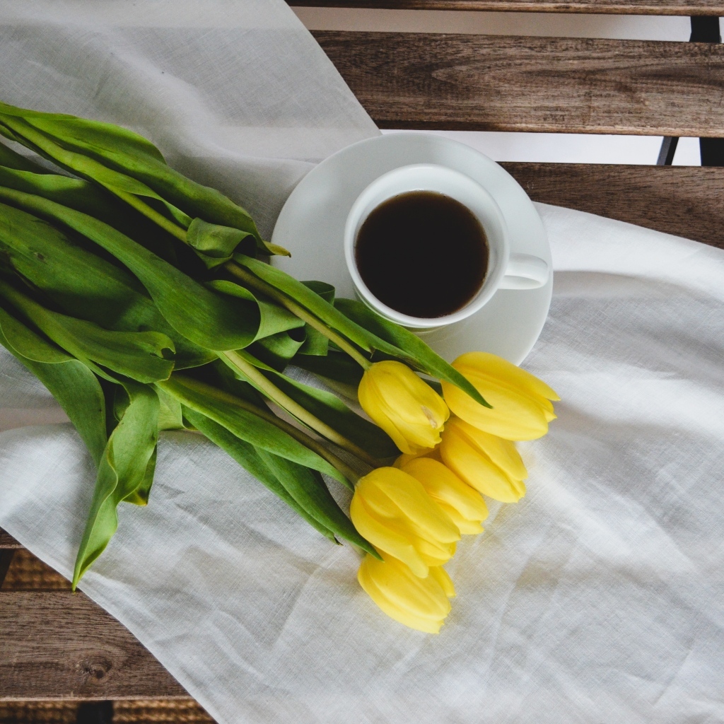Букет желтых тюльпанов с чашкой кофе на лавке
