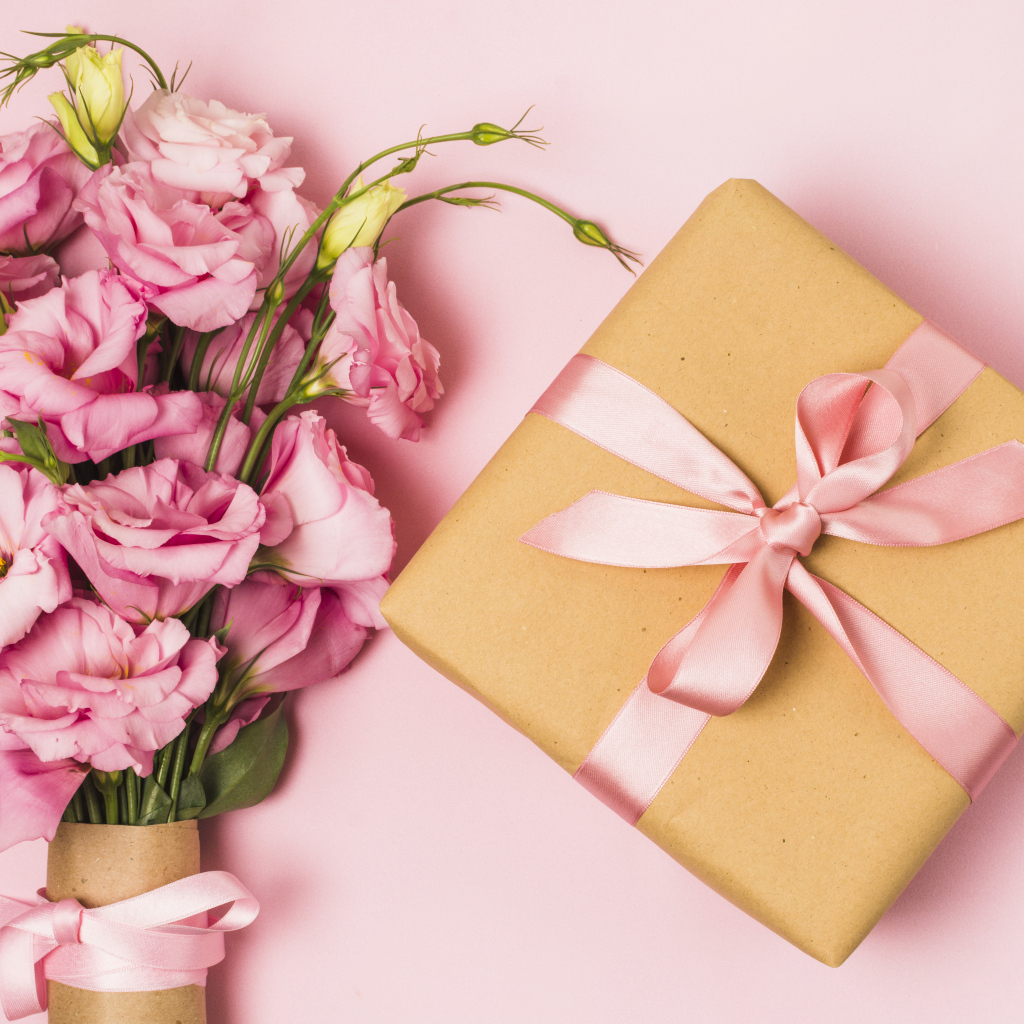 Большой букет эустомы с подарком на розовом фоне