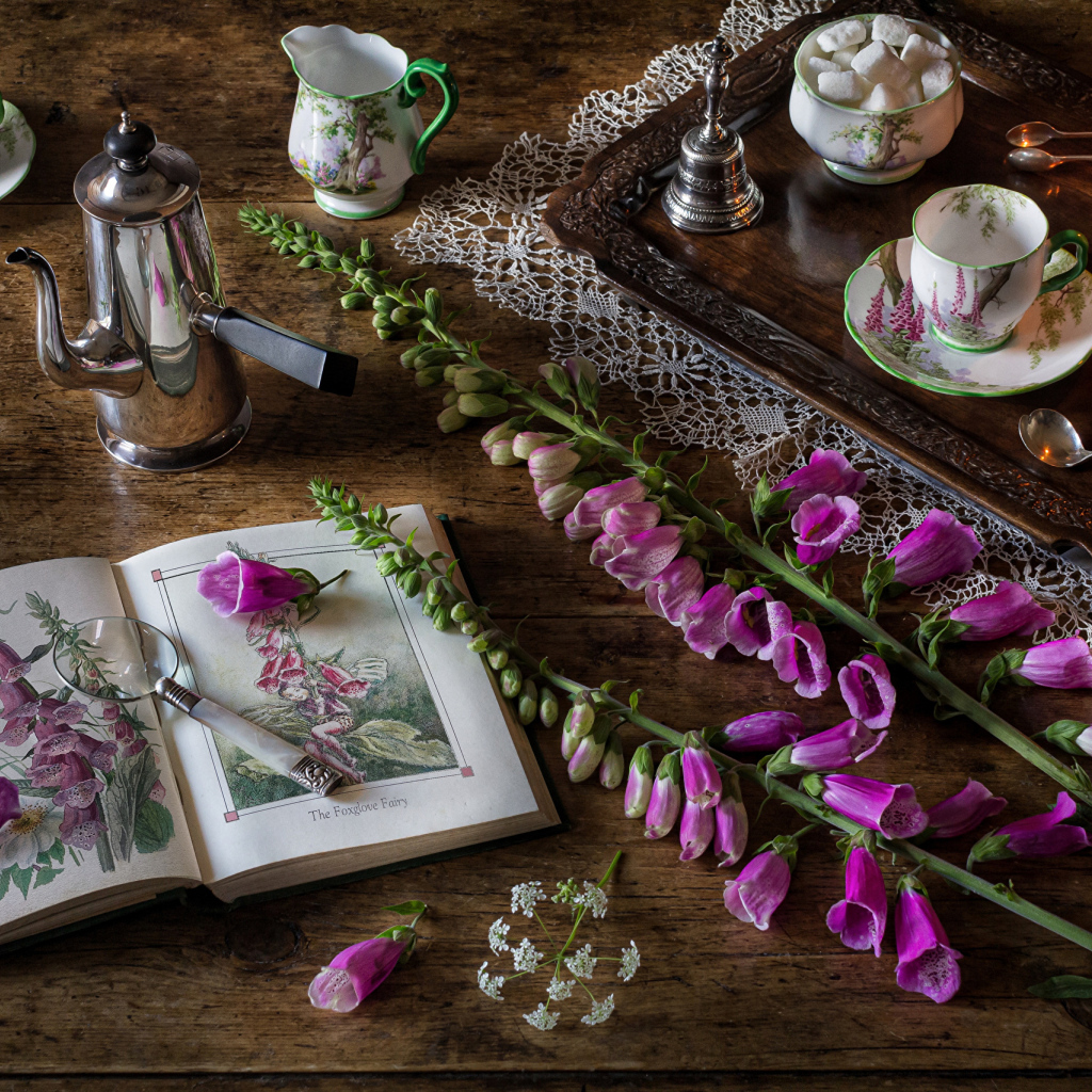 Розовые цветы на столе с книгой и чаем