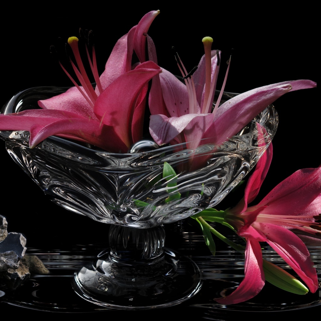 Розовые лилии в стеклянной вазе на столе