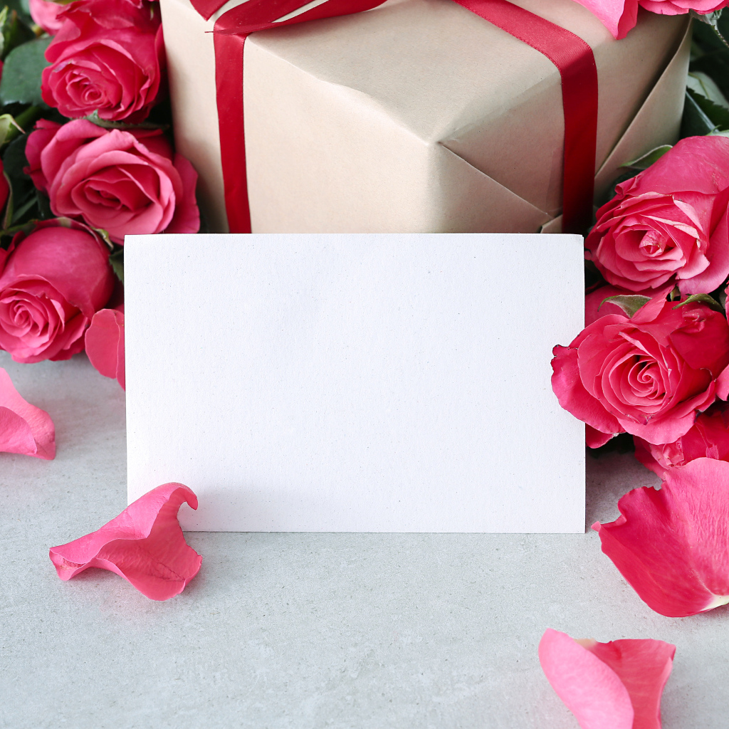 Лист бумаги с розовыми розами и подарком для открытки
