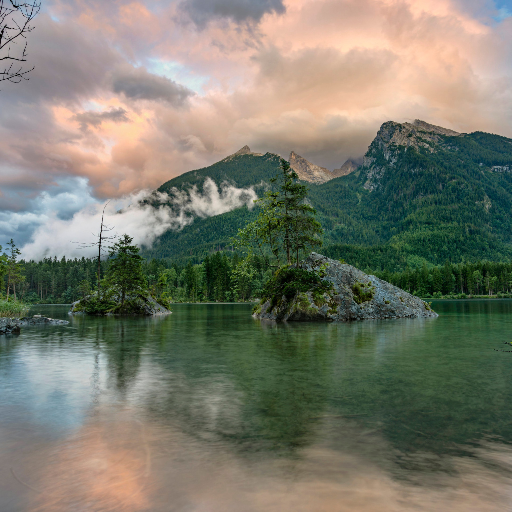 Покрытые зеленью горы в облаках у озера