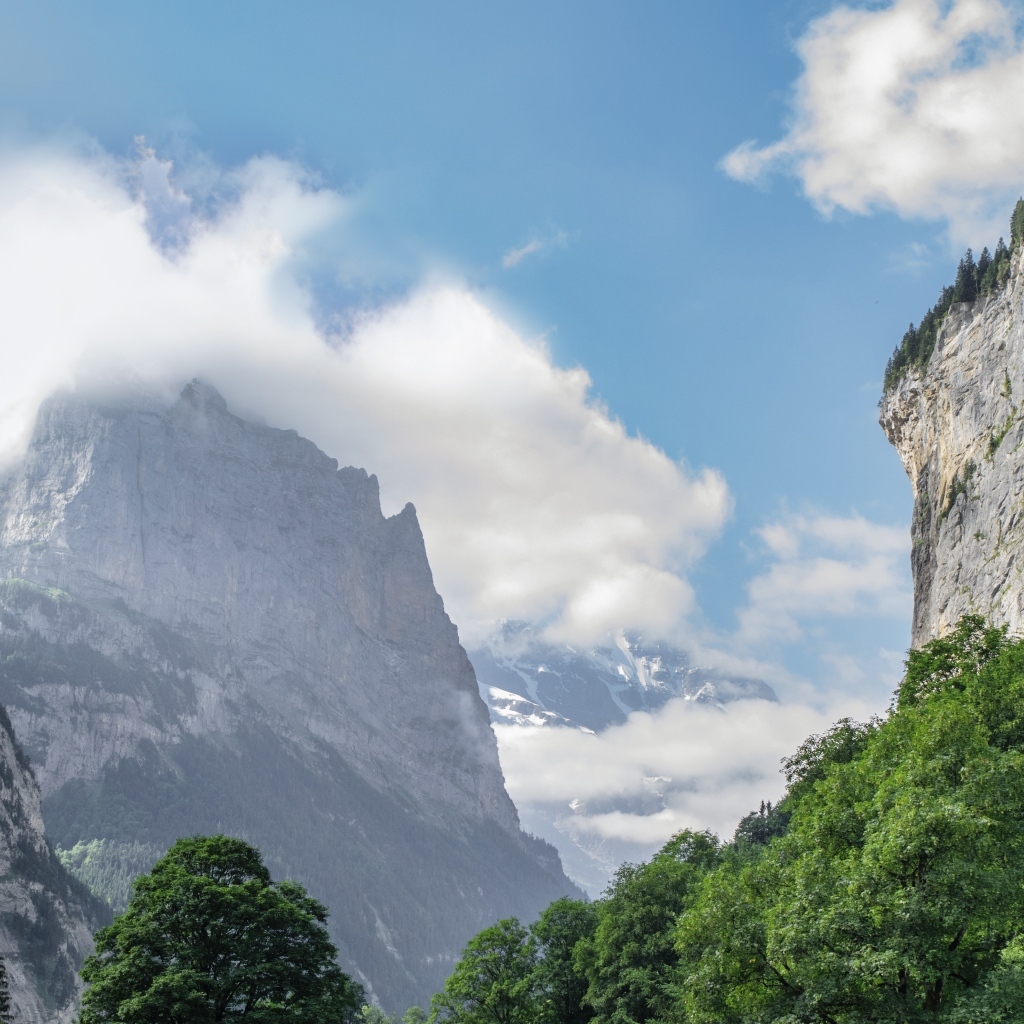 Высокие покрытые зеленью горы в белых облаках