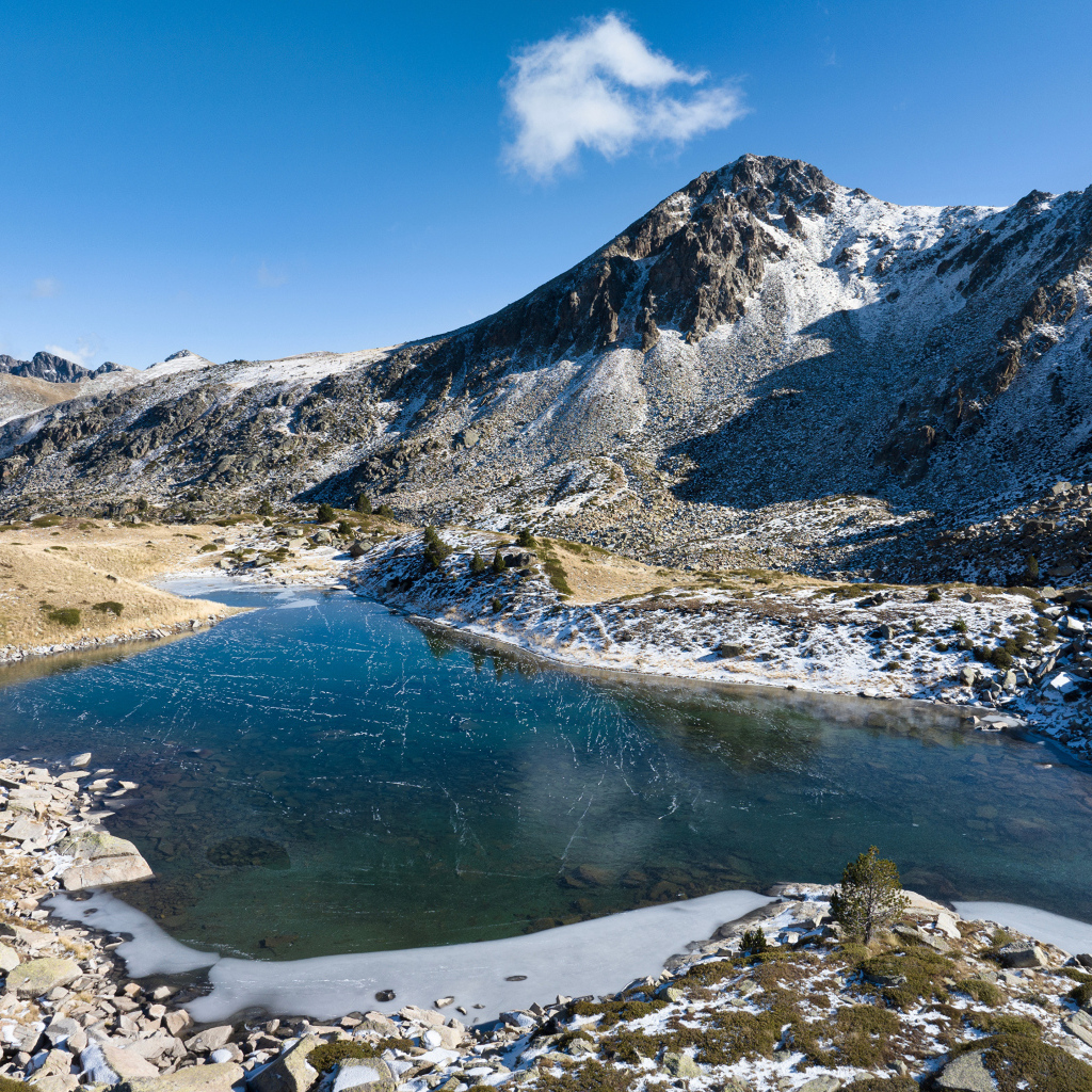 Покрытое льдом озеро в заснеженных горах в лучах солнца, Андорра