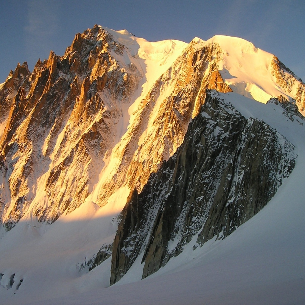Заснеженная высокая гора в лучах яркого солнца