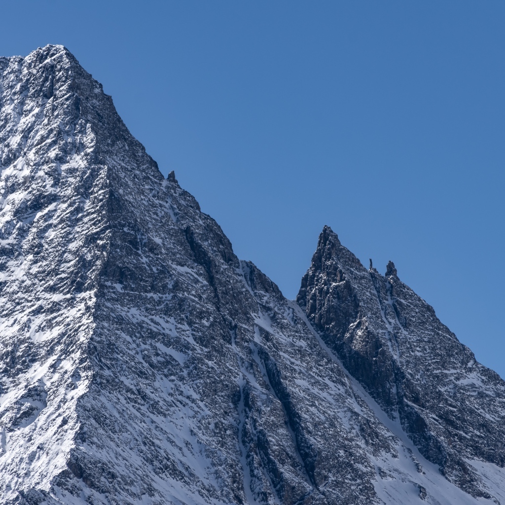 Крутая вершина горы в снегу на фоне голубого неба