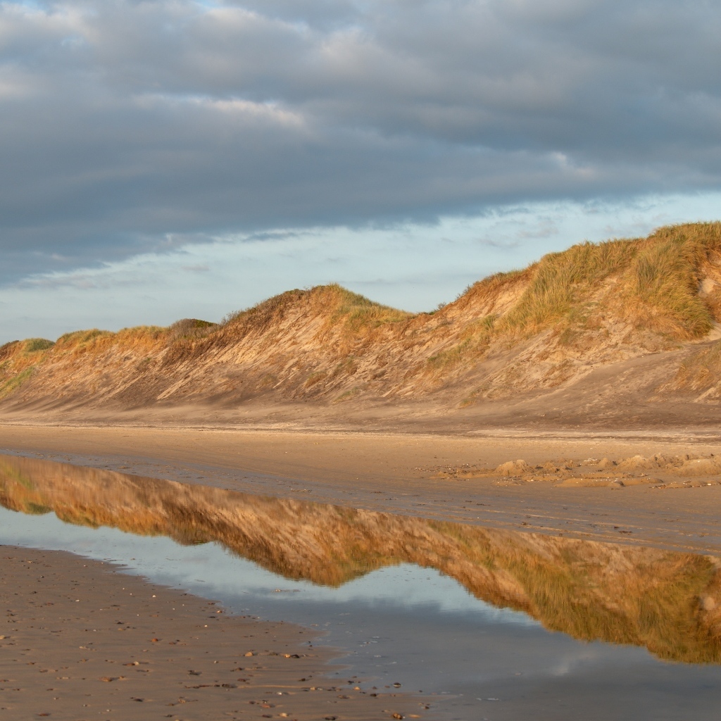 Холты отражаются в реке под грозовым небом