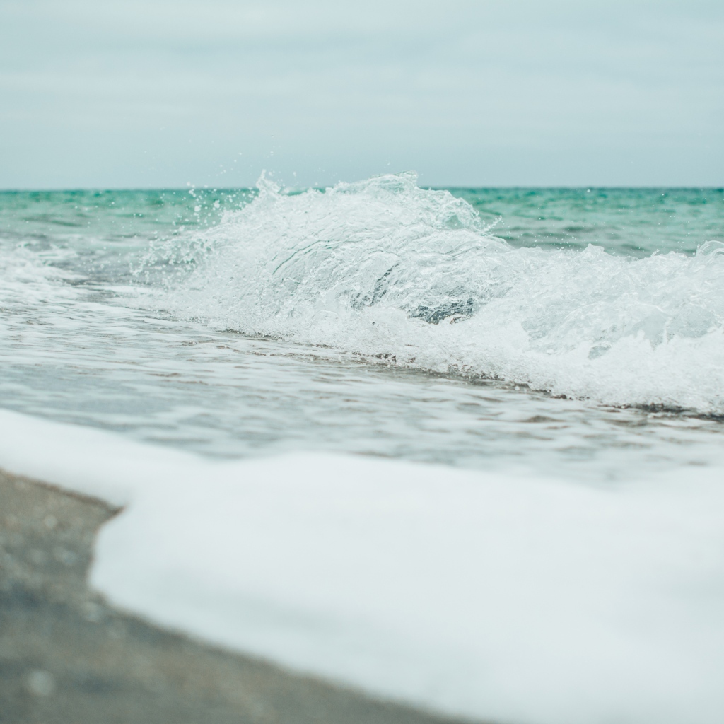 Белая морская пена на морском песке вблизи