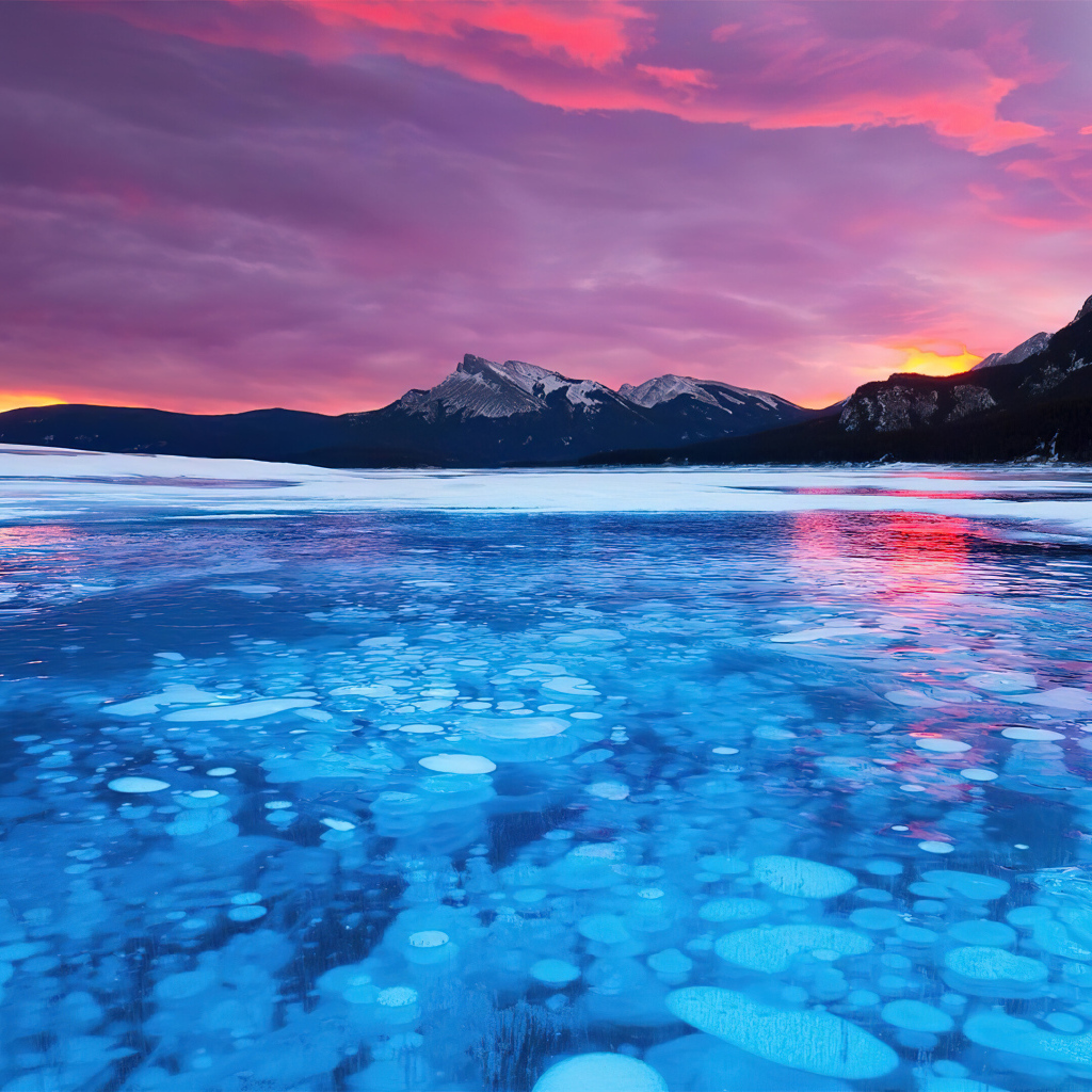 Красный закат солнца над горами у покрытого льдом озера