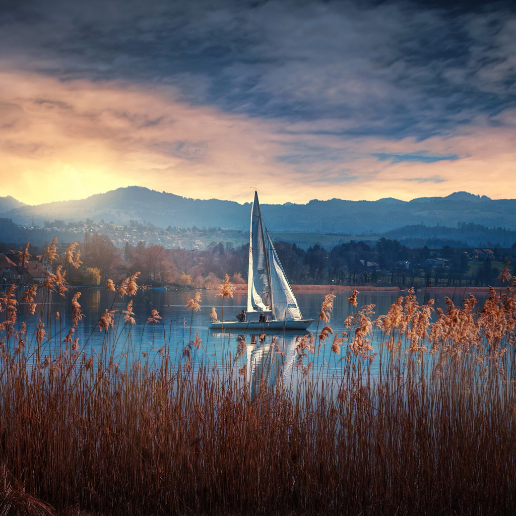 Парусная лодка на озере на закате солнца