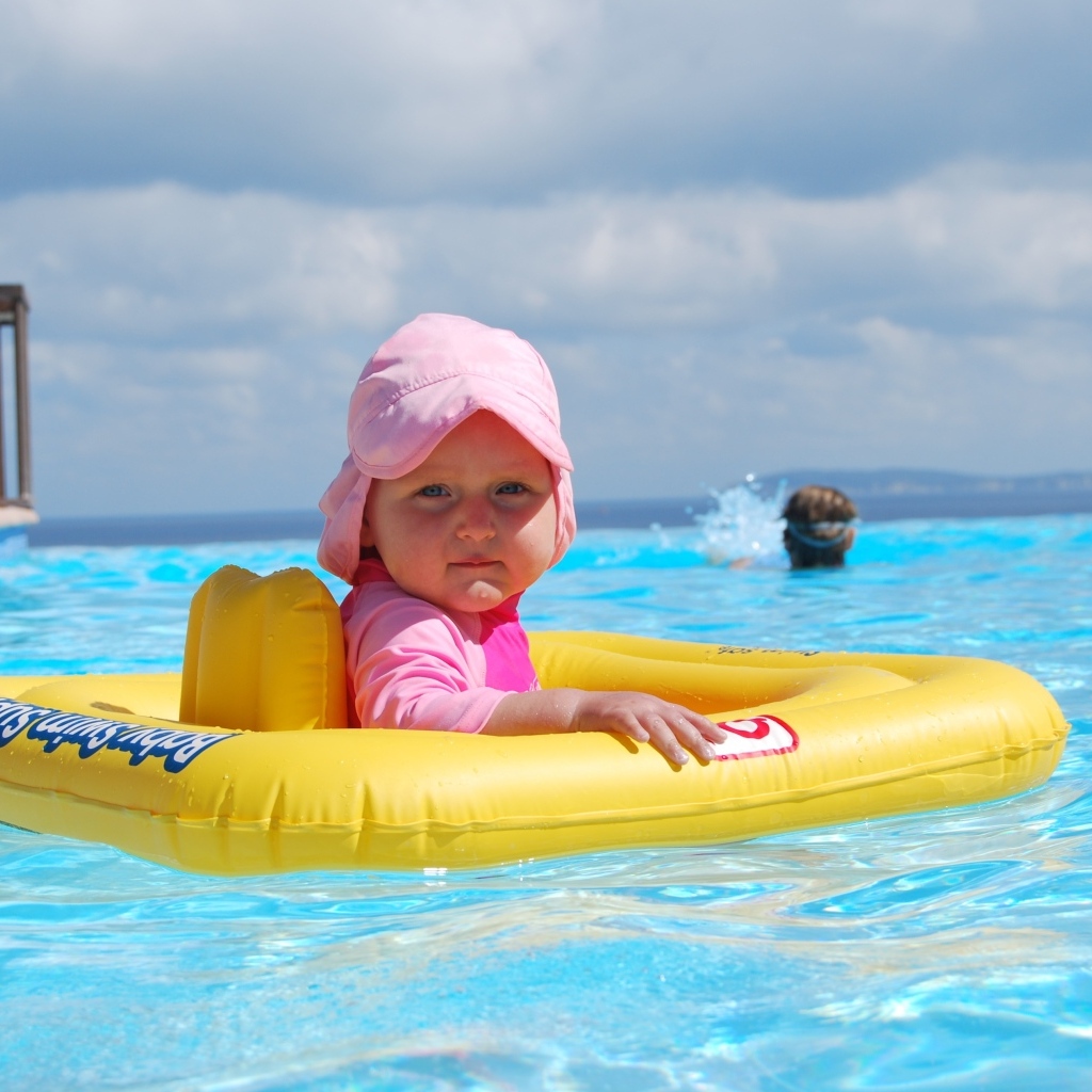 Ребенок со спасательным кругом плавает в бассейне