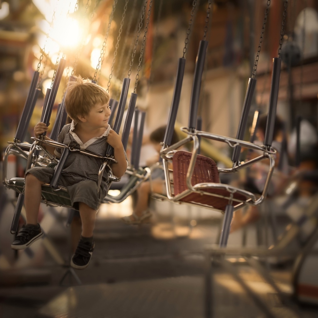 Маленький мальчик катается на каруселях