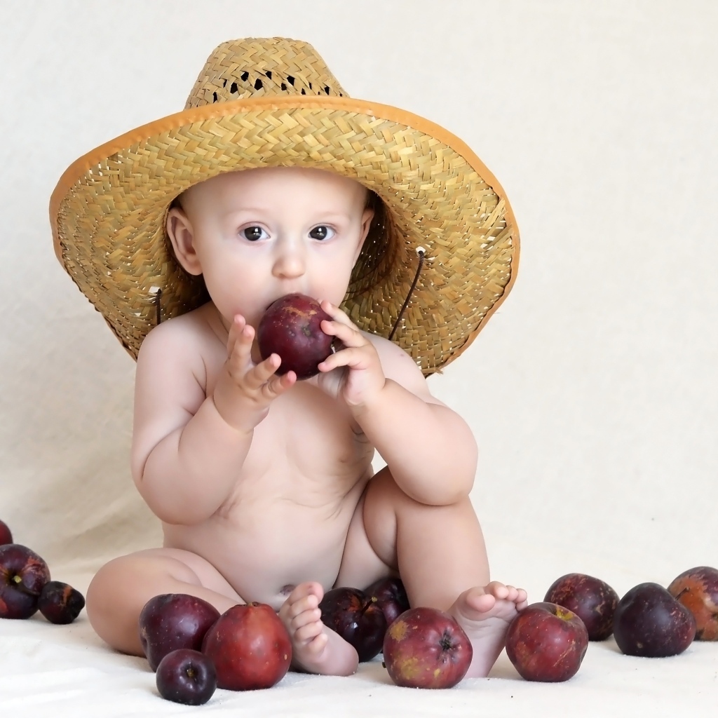 Малыш в шляпе грызет яблоки