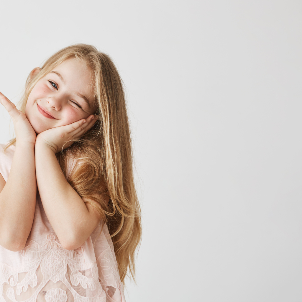 Красивая маленькая длинноволосая девочка на сером фоне