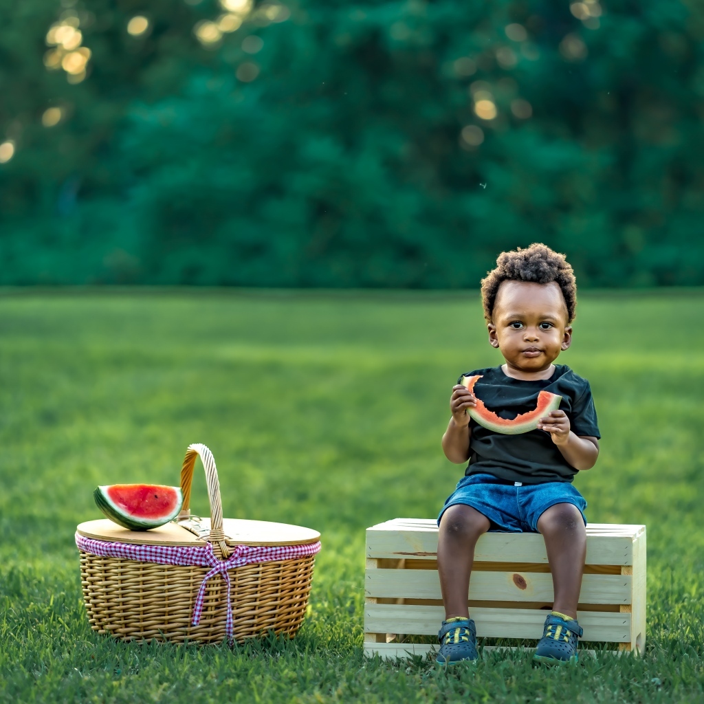 Темнокожий мальчик ест арбуз на природе