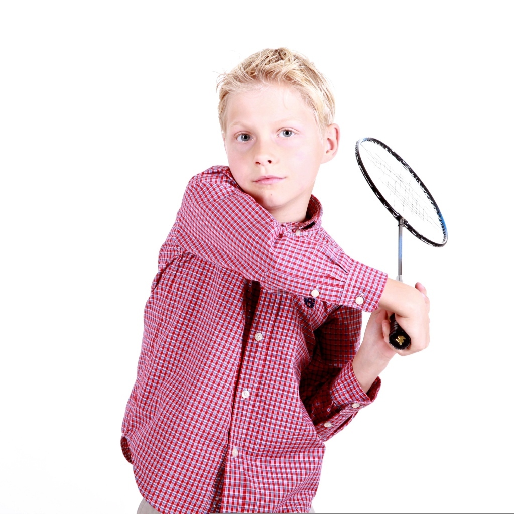 Мальчик в рубашке с ракеткой в руках на белом фоне
