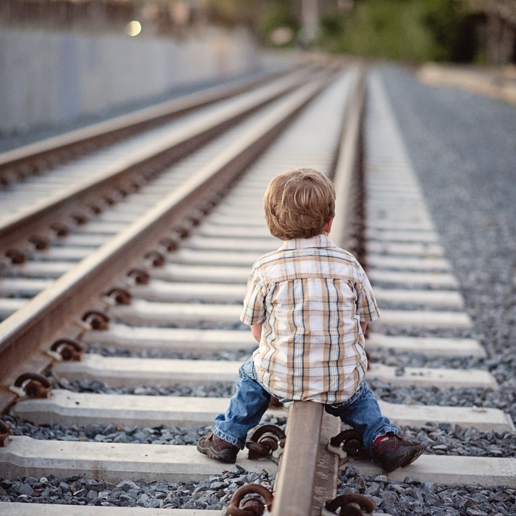 Мальчик сидит на железнодорожных рельсах