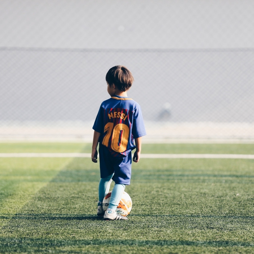 Мальчик футболист с мячом на поле