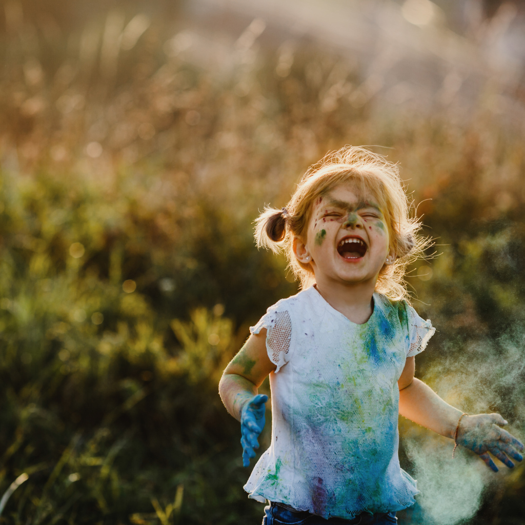 Веселая девочка в краске на улице