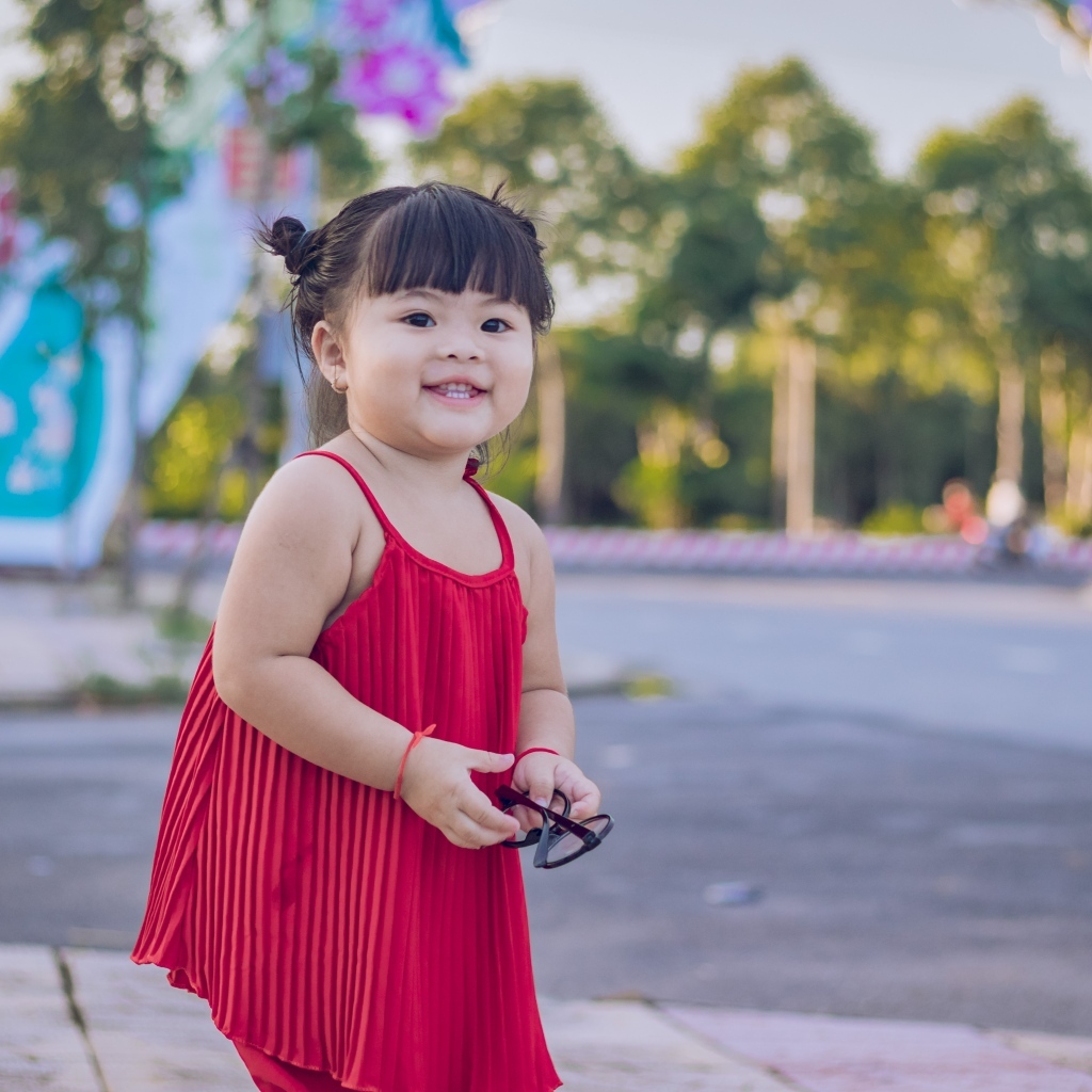 Веселая маленькая девочка азиатка в красном платье