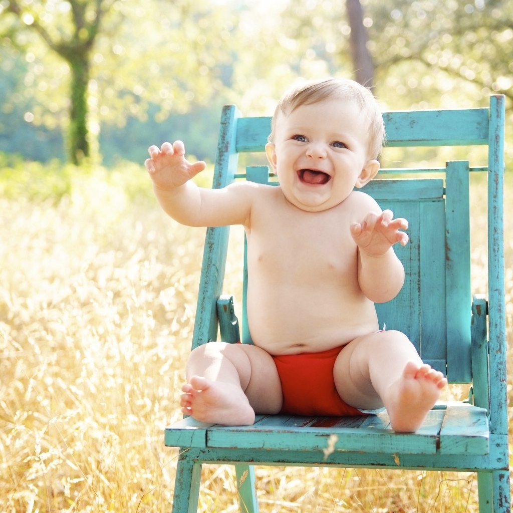 Веселый маленький мальчик в кресле 