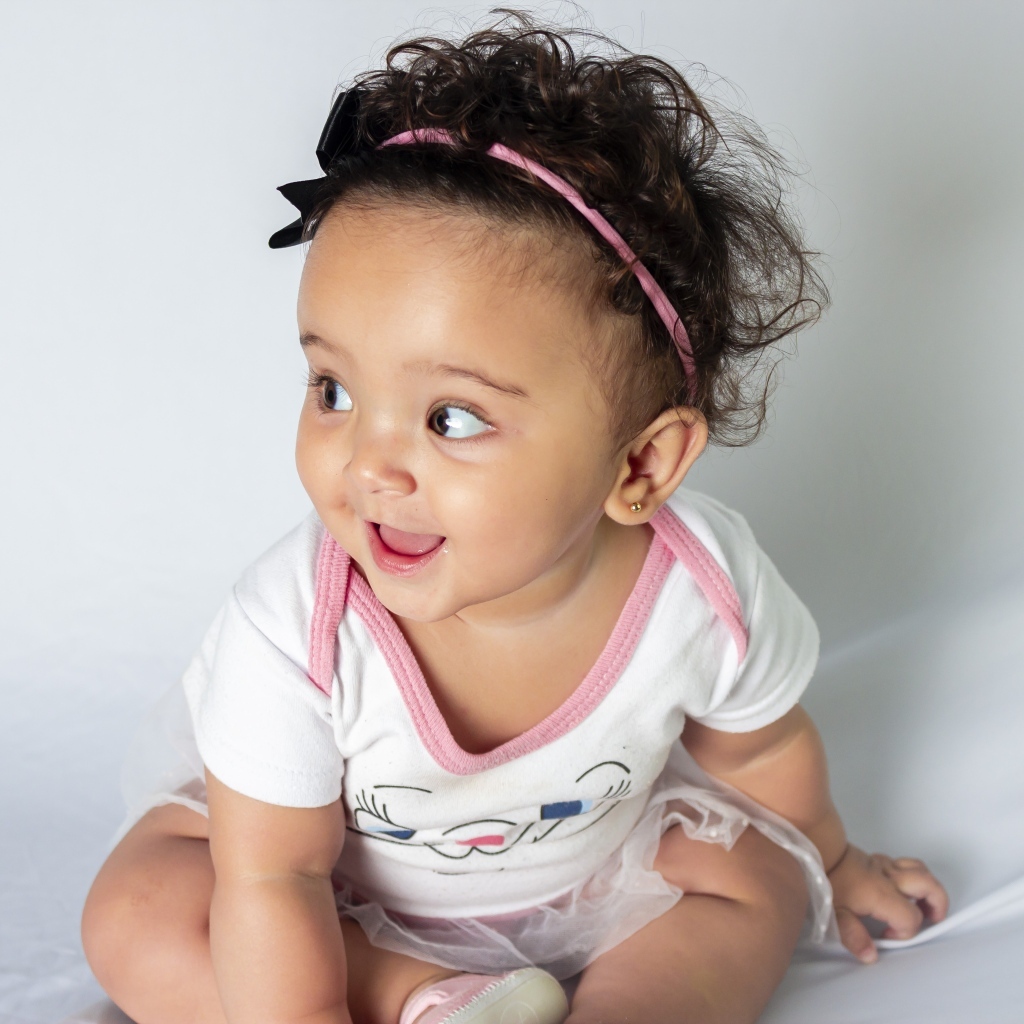 Веселая маленькая девочка с ободком на голове