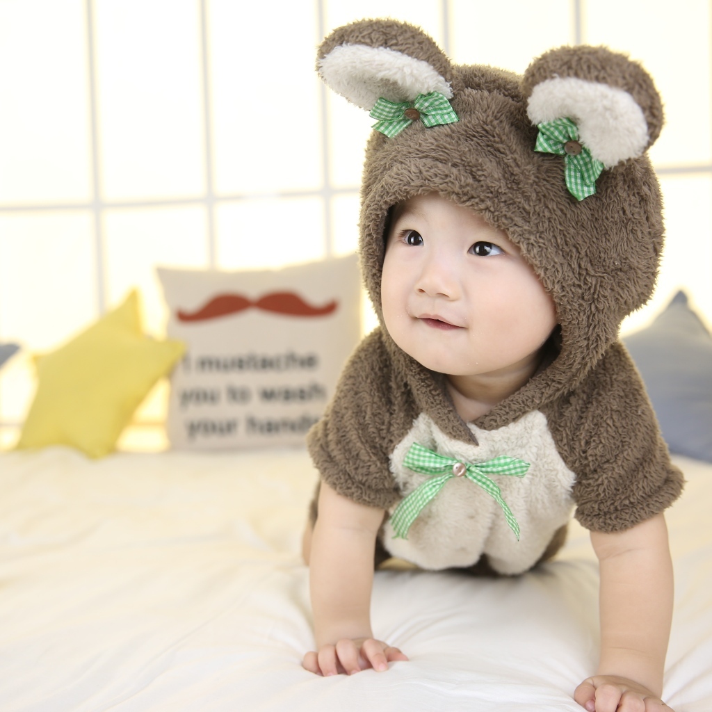 Ребенок в костюме медвежонка на кровати