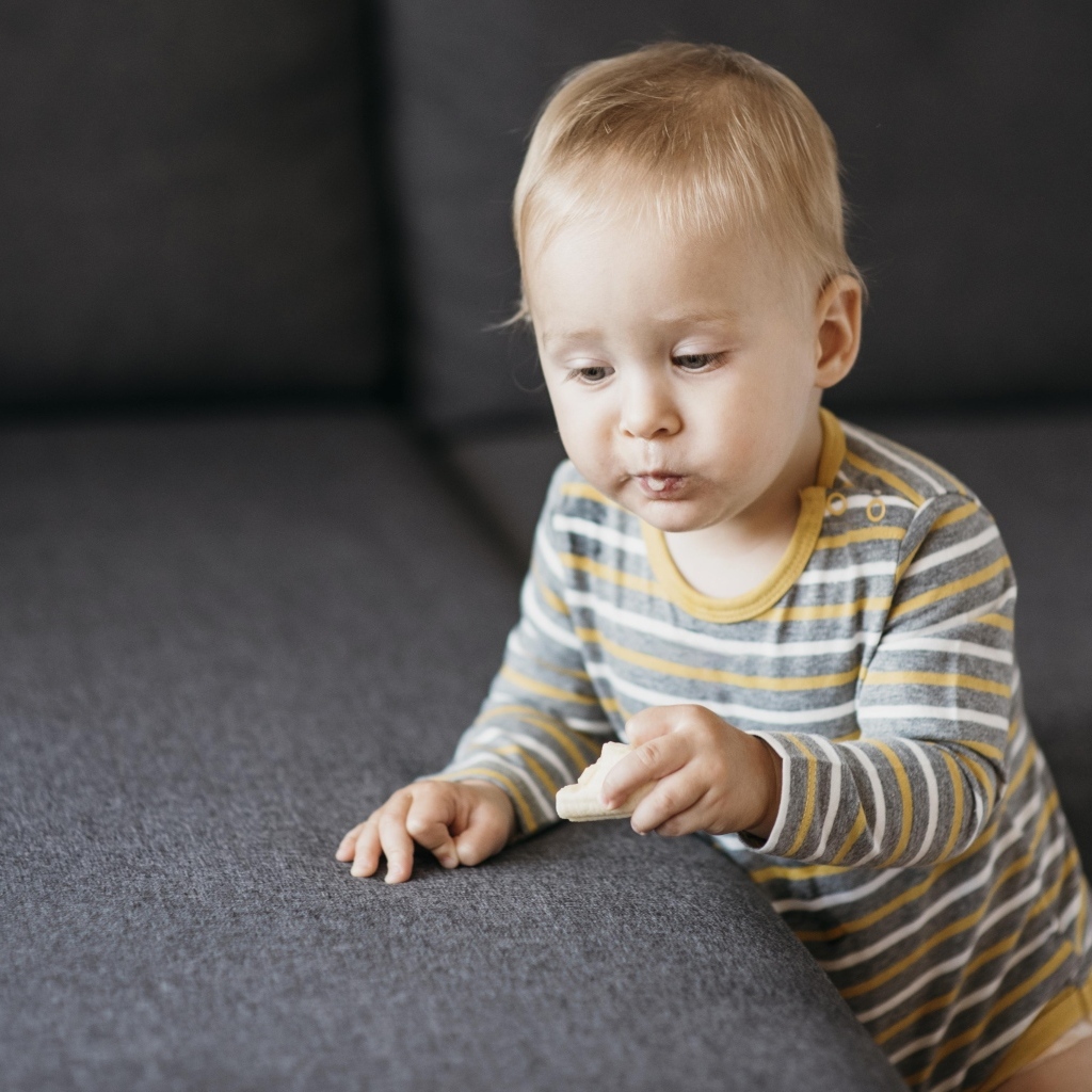 Любопытный маленький ребенок у дивана