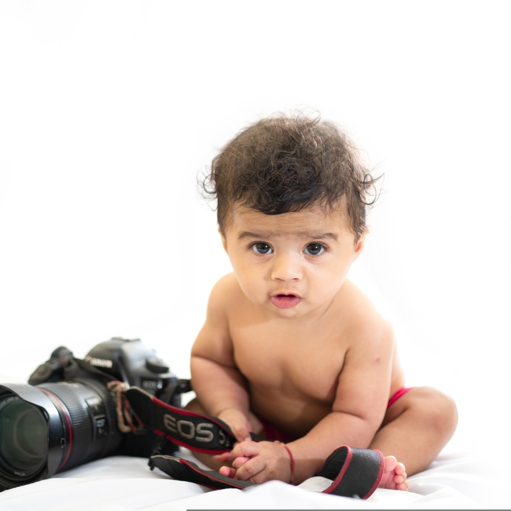 Милый ребенок с фотоаппаратом на белом фоне