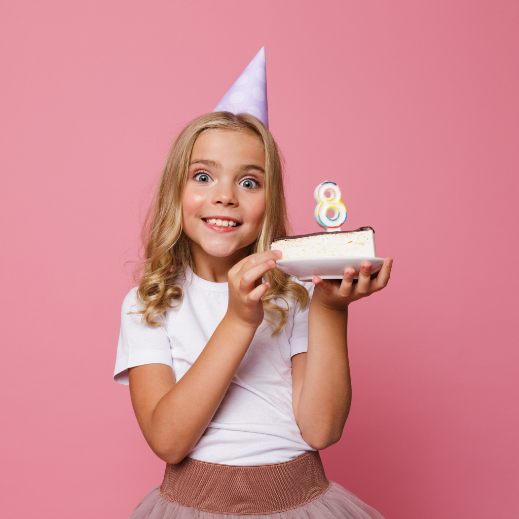 Милая девочка отмечает день рождения на розовом фоне