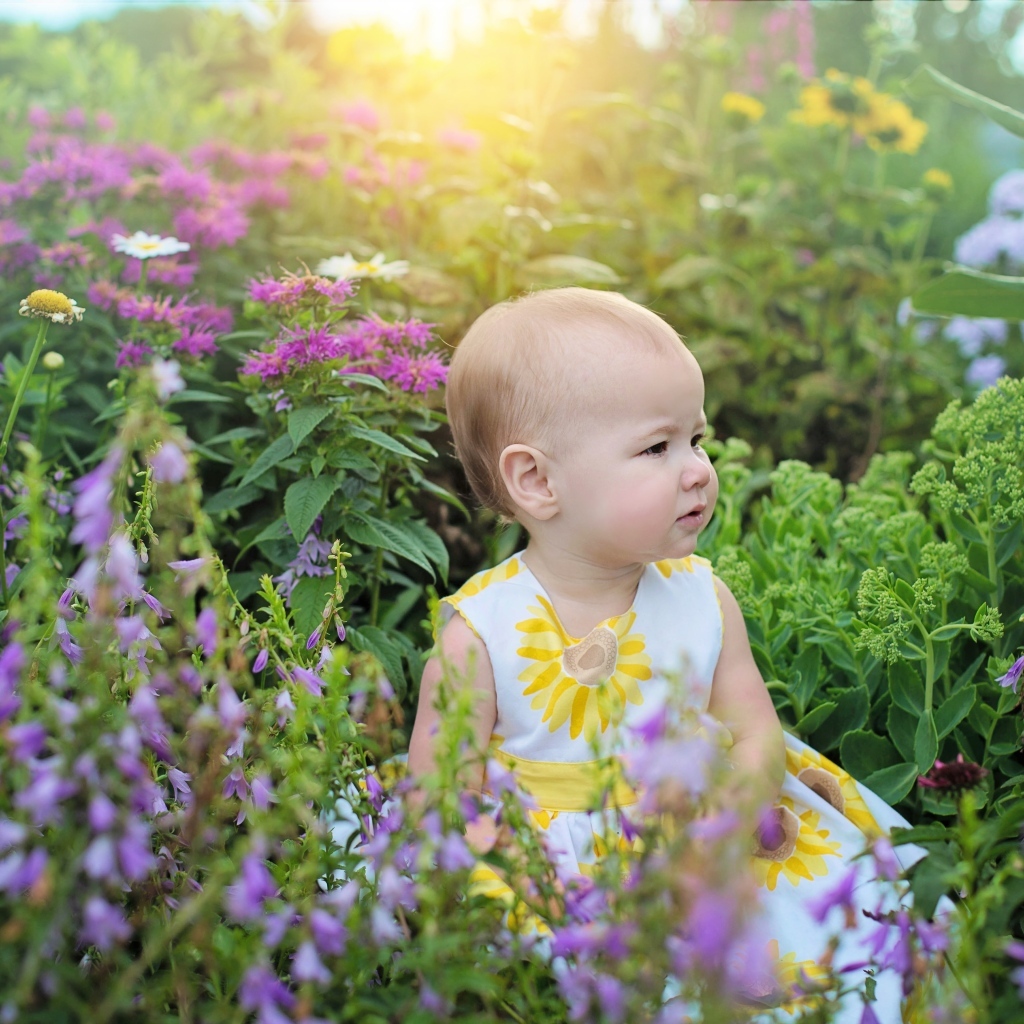 Милая девочка в платье сидит в цветах