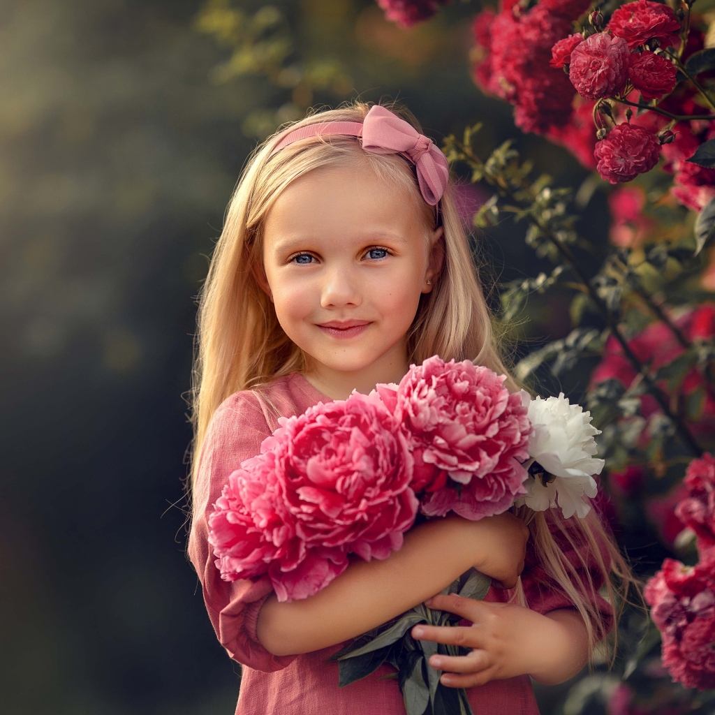 Милая маленькая девочка с букетом пионов